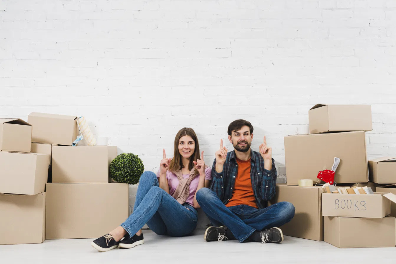 Couple souriant entouré de cartons de déménagement, prêt à louer un box de stockage à Cancon entre Bergerac et Bordeaux